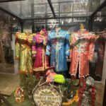 colorful costumes and props from sgt peppers lonely hearts club band in a clear museum case